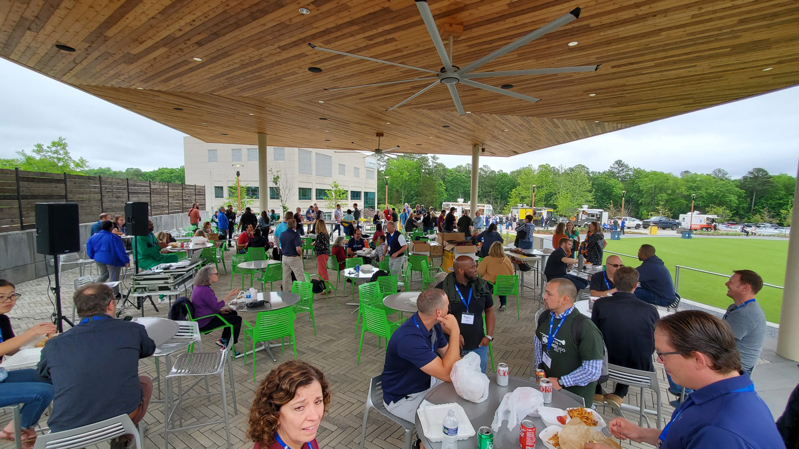 TechExpo attendees sitting at tables enjoying the food and the outdoor setting under the pavilion.